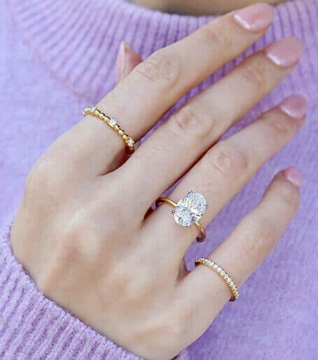 Oval diamond solitaire in yellow gold, worn with gold stacking rings