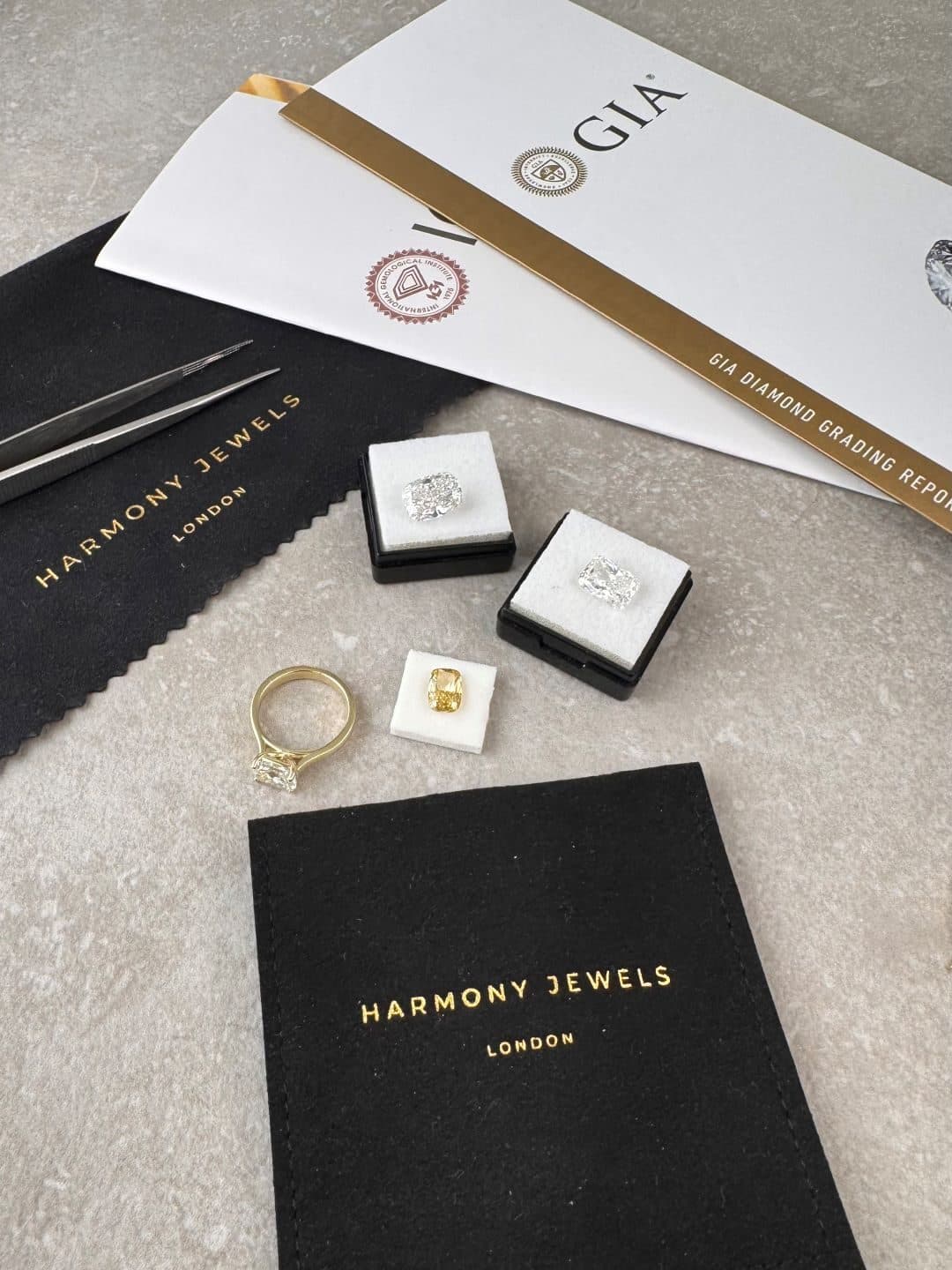 Loose diamonds in presentation boxes with a diamond grading report and a yellow gold ring