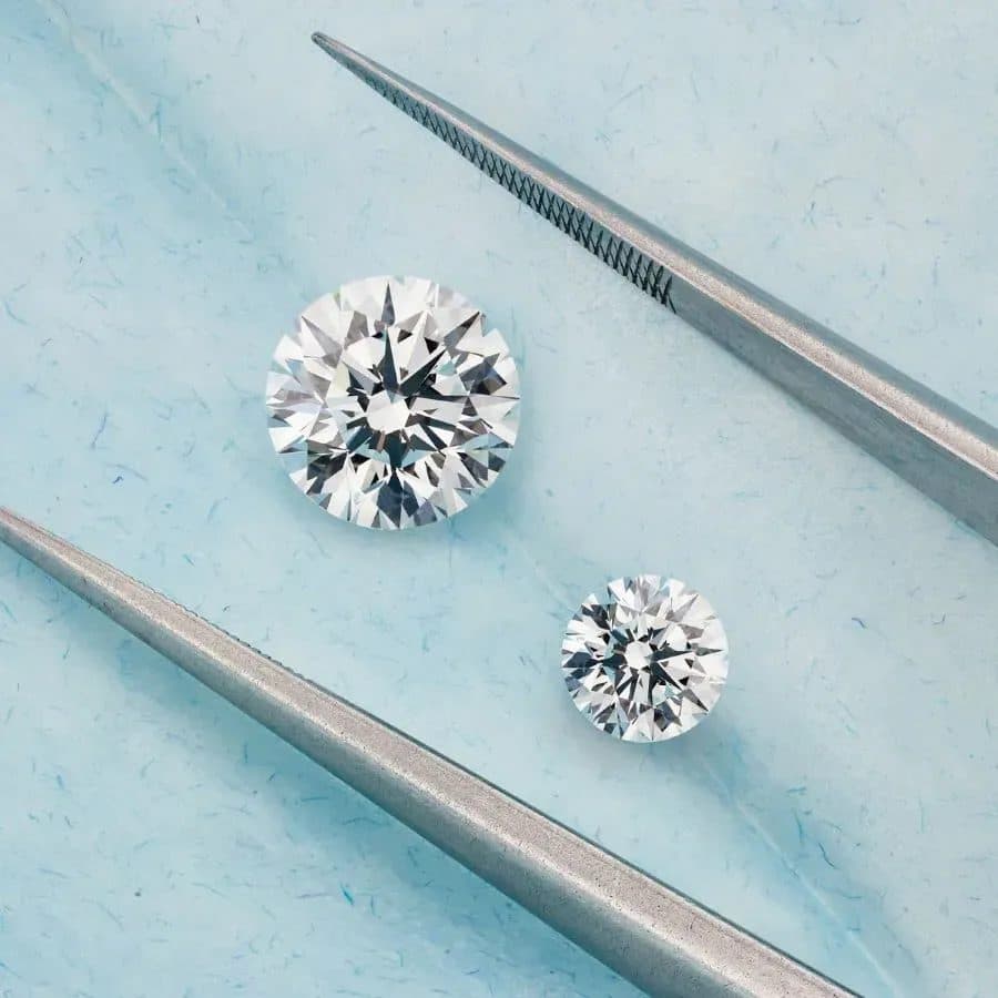 Two round brilliant diamonds with jeweller's tweezers